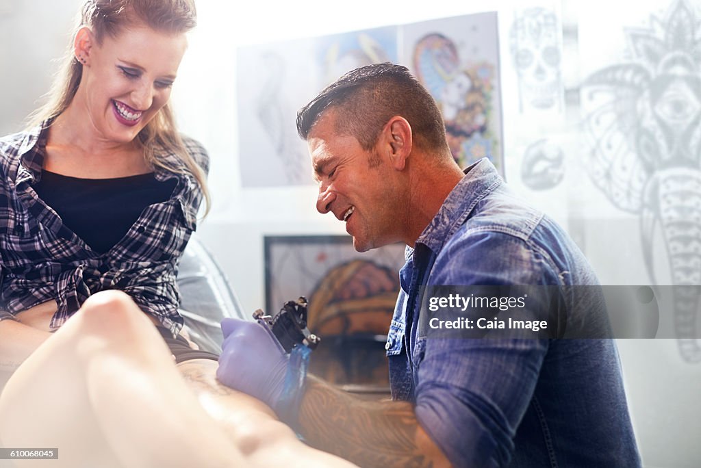 Tattoo artist tattooing womans thigh