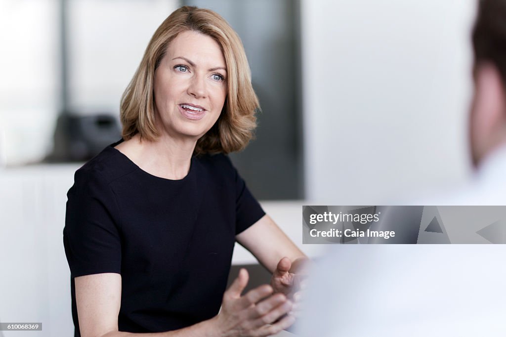 Businesswoman gesturing and talking to businessman