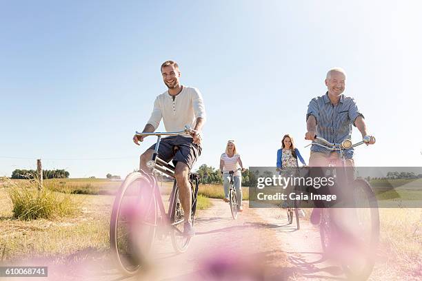 family riding bicycles on sunny rural dirt road - daily life in poland stock-fotos und bilder