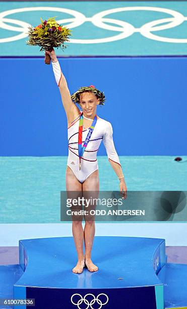 French Emilie Le Pennec celebrates on the podium after winning the gold medal in the women's uneven bars final on August 22, 2004 at the Olympic...