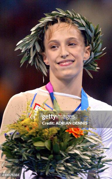 French Emilie Le Pennec celebrates on the podium after winning the gold medal in the women's uneven bars final 22 August 2004 at the Olympic Indoor...