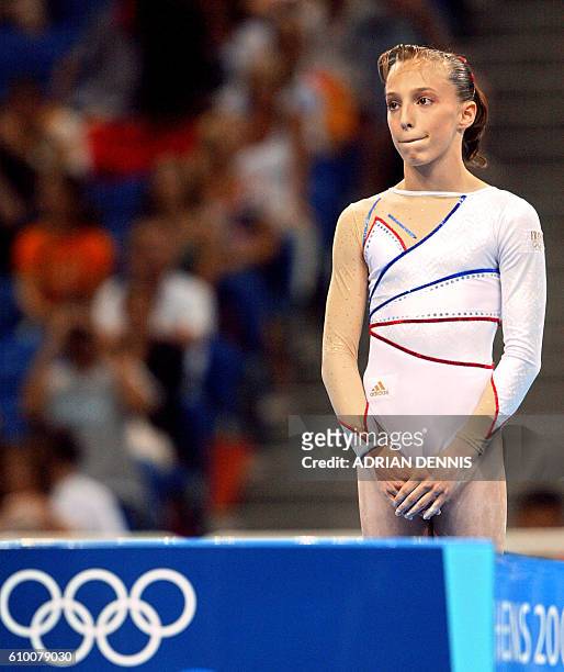 French Emilie Le Pennec stands in front of the podium after winning the gold medal in the women's uneven bars final on August 22, 2004 at the Olympic...
