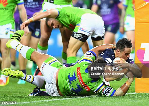 Cooper Cronk of the Storm breaks through a tackle by Josh Papalii of the Raiders to score a try during the NRL Preliminary Final match between the...