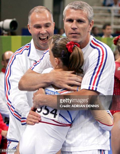 French Emilie Le Pennec is congratulated by her coach Yves Kieffer after winning the gold medal in the women's uneven bars final 22 August 2004 at...