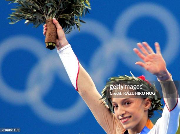 French Emilie Le Pennec celebrates on the podium after winning the gold medal in the women's uneven bars final on August 22, 2004 at the Olympic...