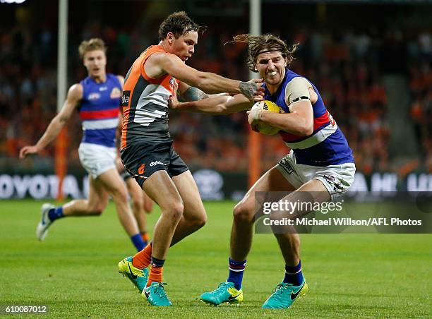 Marcus Bontempelli of the Bulldogs fends off Nathan Wilson of the Giants during the 2016 AFL First Preliminary Final match between the GWS Giants and...