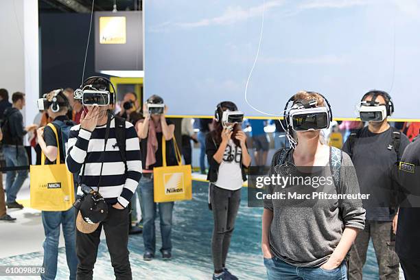 Visitors are trying out the Zeiss VR One Plus video glasses at the 2016 Photokina trade fair on September 24, 2016 in Cologne, Germany. Photokina is...