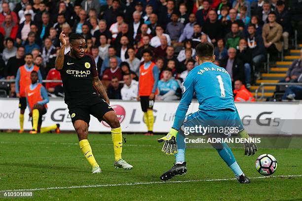 Manchester City's English midfielder Raheem Sterling slots the ball past Swansea City's Polish goalkeeper Lukasz Fabianski to score their third goal...