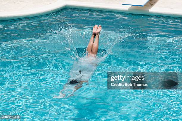 young woman diving into a swimming pool - sprung ins wasser stock-fotos und bilder