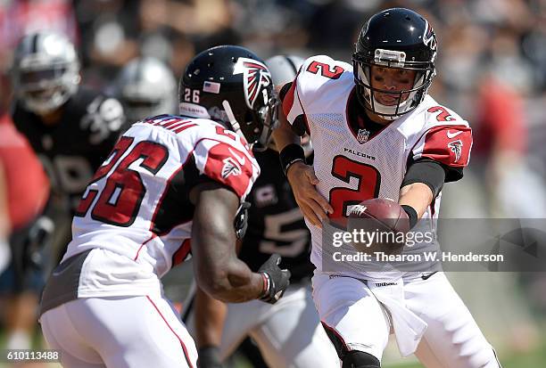 Matt Ryan of the Atlanta Falcons turns to hand the ball off to running back Tevin Coleman against the Oakland Raiders in the first haft of their NFL...