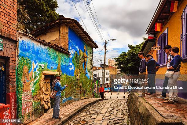 bogotá, colombia - a tour guide explains a legend to tourists on the narrow, colorful, cobblestoned calle del embudo in the historic la candelaria district - la candelaria bogota stockfoto's en -beelden