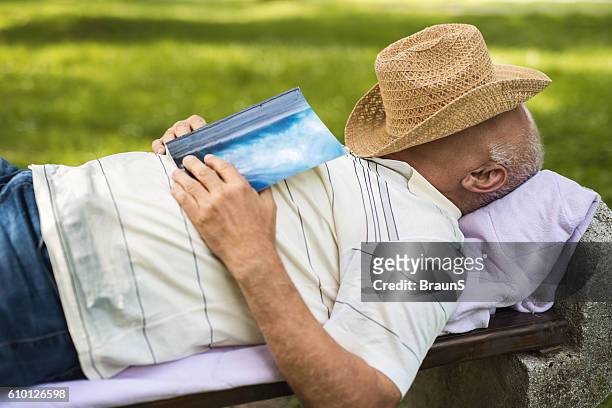 lässig alter mann ein nickerchen auf einer bank im freien. - bank müde frühling stock-fotos und bilder