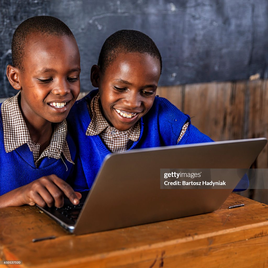 Niños africanos usando una computadora portátil dentro del aula, Kenia