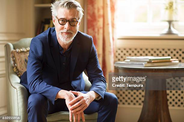 high class mature man portrait at home. - white business suit stockfoto's en -beelden