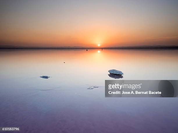saltwater lake with salt formations, in a sunset with water reflections orange - horizon over land 個照片及圖片檔