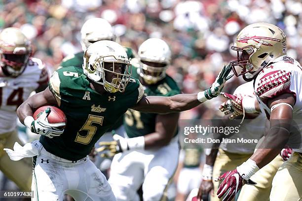 Runningback Marlon Mack of the South Florida Bulls stiff arms Defensive End DeMarcus Walker of the Florida State Seminoles on a running play during...