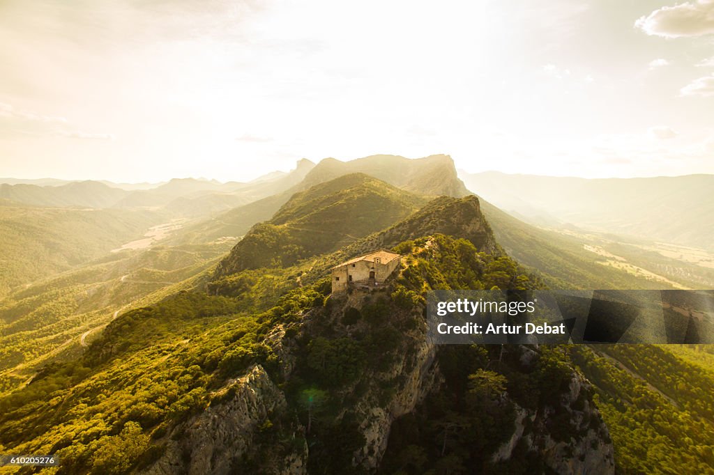 Aerial view of a beautiful church on top of mountain with stunning summits on sunset light in the Catalan Pyrenees.