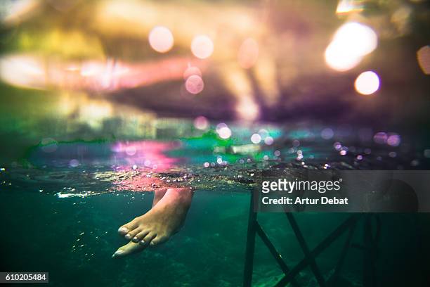 underwater view of a feet girl sitting on beach dock contemplating the view in the mediterranean sea costa brava during summer vacations. - cap de creus stock pictures, royalty-free photos & images