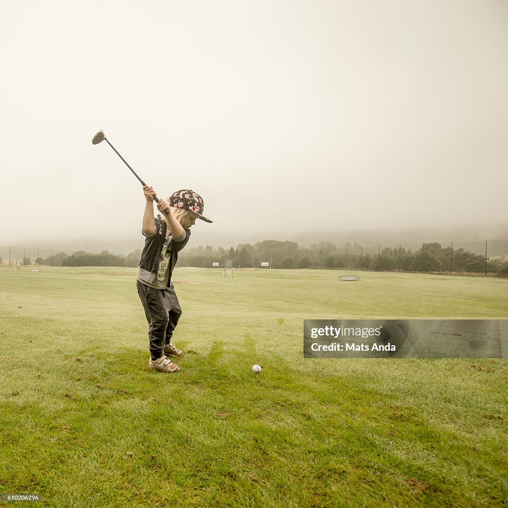 Boy playing golf at the driving range