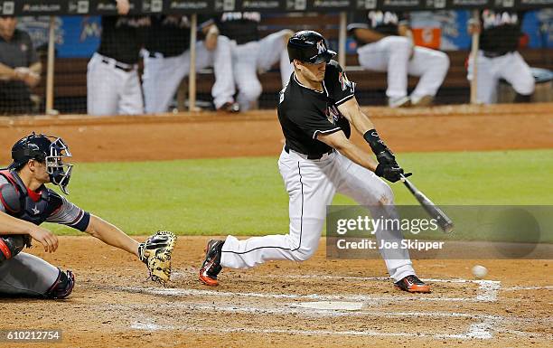 Realmuto of the Miami Marlins hits an RBI single in the seventh inning in front catcher Anthony Recker of the Atlanta Braves at Marlins Park on...