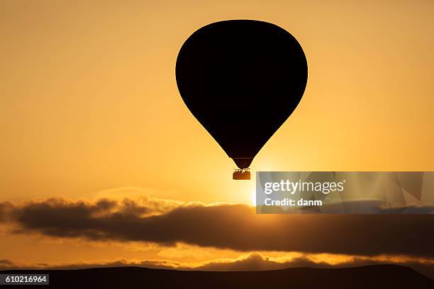 silhouette of balloon over sunrise in cappadocia, turkye - turkye photos et images de collection