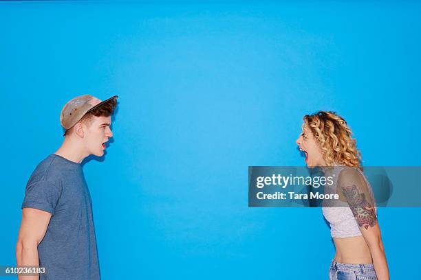 young man and woman shouting at each other - chico gritando abriendo la boca fotografías e imágenes de stock