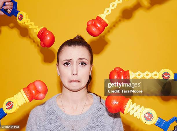 woman being punched by toy gloves - boxing glove coloured background stock pictures, royalty-free photos & images