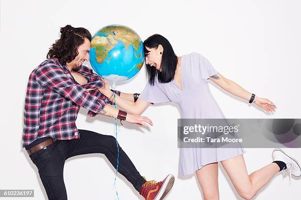 man and woman play fighting with world balloon - frau globus stock-fotos und bilder