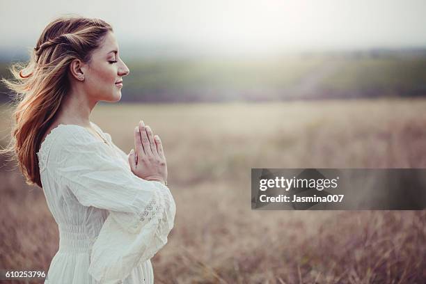 schöne frau auf einer wiese - women prayer stock-fotos und bilder