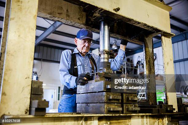 senior farmer operating hydraulic press - hebebühne stock-fotos und bilder
