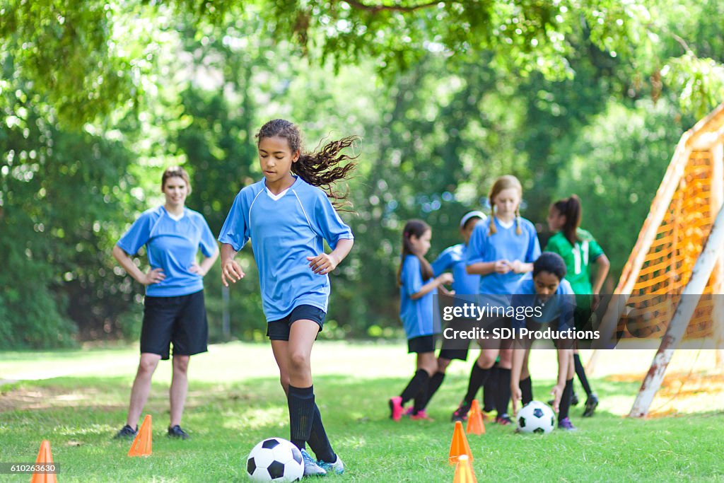 Talented soccer player kicks ball around practice cones