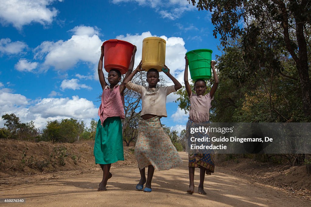 Girls carrying water buckets at a borehole in Malawi