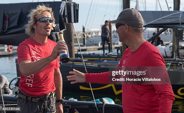 Ceeref boat owner Igor Lah hands a crew member a bottle of champagne in celebration of having won the first race of the day during Fleet Race on the...