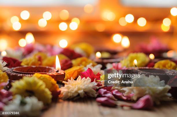 diya lamps lit during diwali celebration with flowers and sweets in background - diya oil lamp fotografías e imágenes de stock