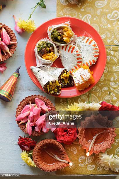 diya lamps lit during diwali celebration with flowers and sweets in background - diwali sweets stock-fotos und bilder