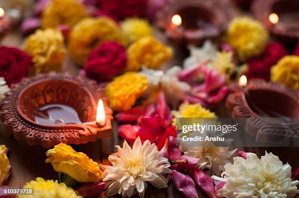 diya lamps lit during diwali celebration with flowers and sweets in background - clay oil lamps fotografías e imágenes de stock
