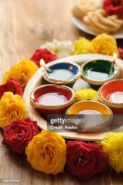 diya lamps lit during diwali celebration with flowers and sweets in background - indian dessert stock-fotos und bilder