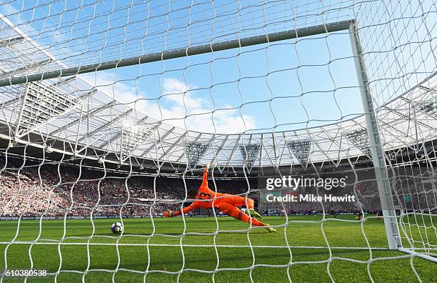 Adrian of West Ham United dives in vain as Charlie Austin of Southampton scores their first goal during the Premier League match between West Ham...