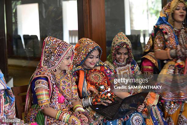 Indian folk dancers from the Panghat Group of Performing Arts use a laptop as they take a break during a dress rehearsal for an event to mark the...