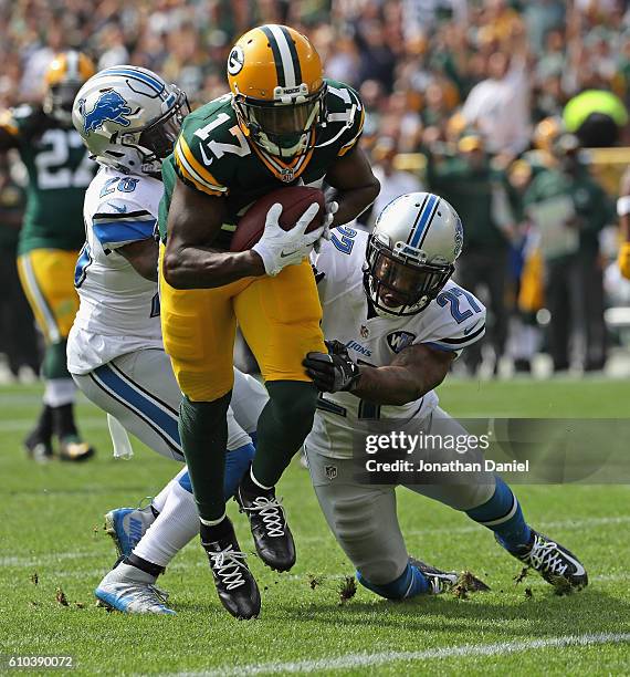 Davante Adams of the Green Bay Packers breaks a tackle attempt by Glover Quin and Quandre Diggs of the Detroit Lions to score a first quarter...