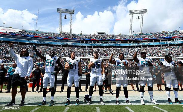 Jacksonville Jaguars players raise their arms in protest during the National Anthem prior to the game against the Baltimore Ravens at EverBank Field...