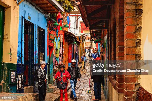 bogoté, kolumbien - lokale kolumbianische touristen gehen durch die enge, bunte, gepflasterte calle del embudo im historischen stadtteil la candelaria - embudo stock-fotos und bilder