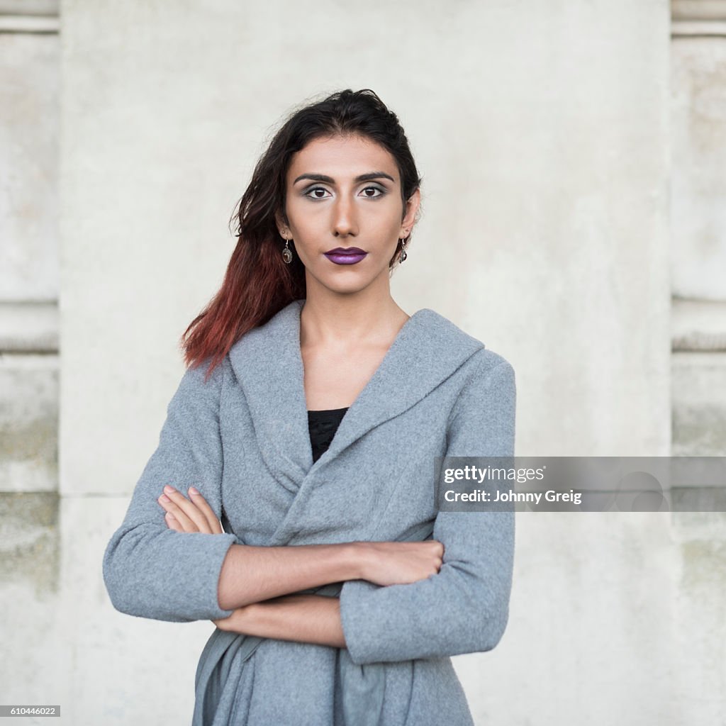 Portrait d’une femme transgenre face à une caméra, les bras croisés