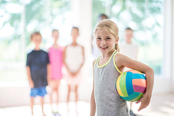 little girl standing with a volleyball - girls volleyball stock pictures, royalty-free photos & images