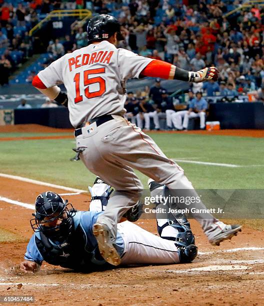 Dustin Pedroia of the Boston Red Sox jumps to avoid the tag of Luke Maile of the Tampa Bay Rays at home plate in the tenth inning to score the...