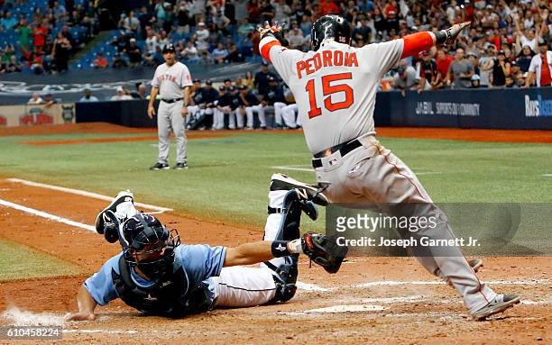 Luke Maile of the Tampa Bay Rays tries to make the tag on Dustin Pedroia of the Boston Red Sox at home plate as Pedroia scores the winning run in the...