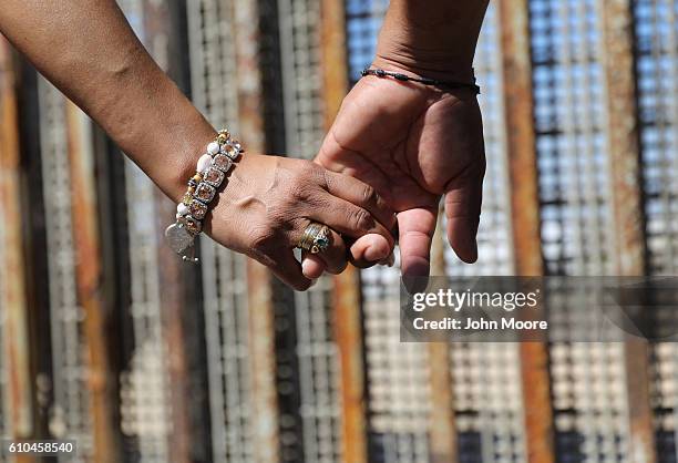 Couple holds hands while meeting loved ones through the U.S.-Mexico border fence on September 25, 2016 in Tijuana, Mexico. The U.S. Border Patrol...