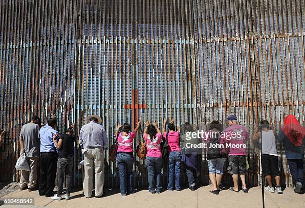 Immigrant activists pray at the U.S.-Mexico border fence on September 25, 2016 in Tijuana, Mexico. The U.S. Border Patrol opens the park on the...