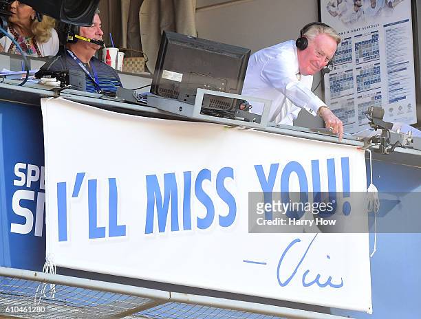 Los Angeles Dodgers announcer Vin Scully points to the sign as he receives an applause during the seventh inning stretch against the Colorado Rockies...