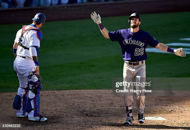 David Dahl of the Colorado Rockies celebrates his solo homerun in front of Yasmani Grandal of the Los Angeles Dodgers to take a 3-2 lead during the...